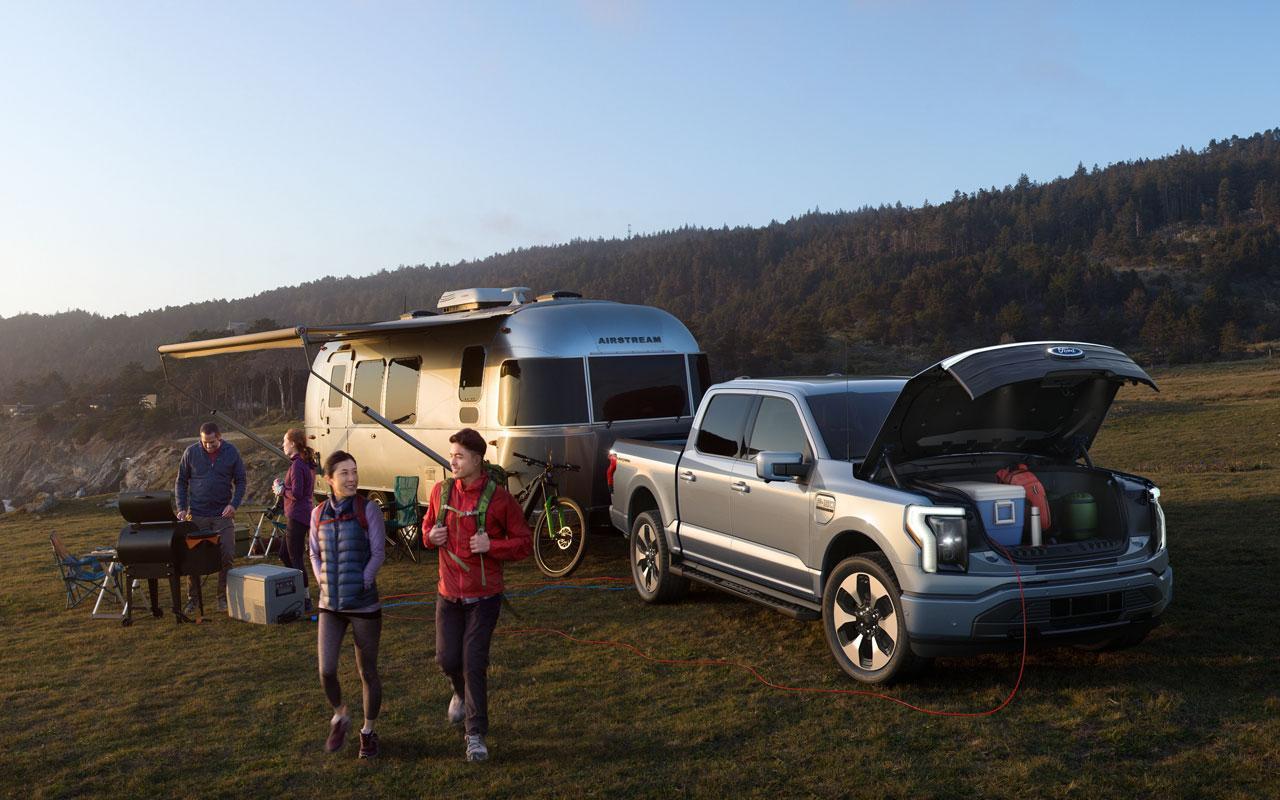 2022 Ford F-150 Lightning connected to an Airstream camper while a couple is about to go hiking