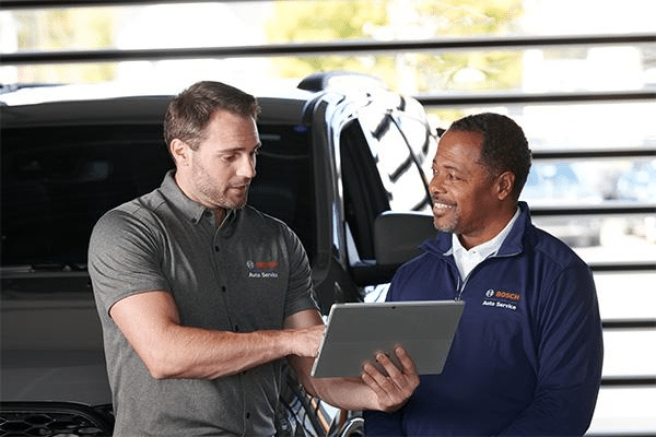 Bosch Auto Service consultant and owner standing by vehicle