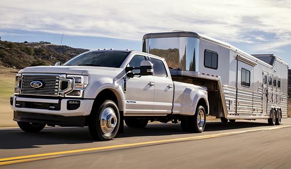 2022 Ford Super Duty® LARIAT F-350 in Oxford White towing large trailer on the road