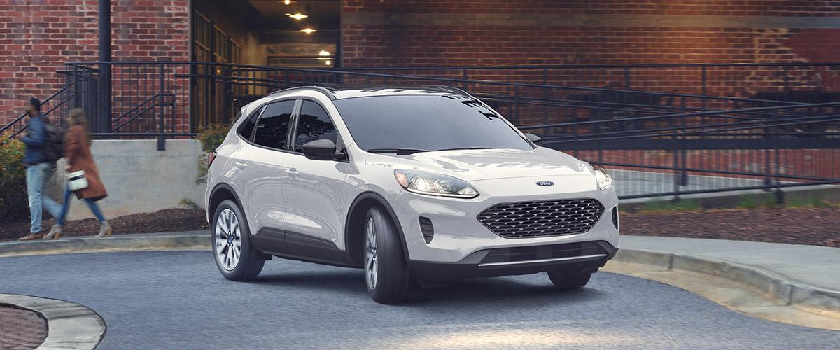 frontal view of white Ford Escape crossover parked in front of a red brick building